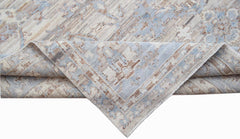 A handwoven transitional Oushak rug featuring a distressed pattern in shades of blue and beige.