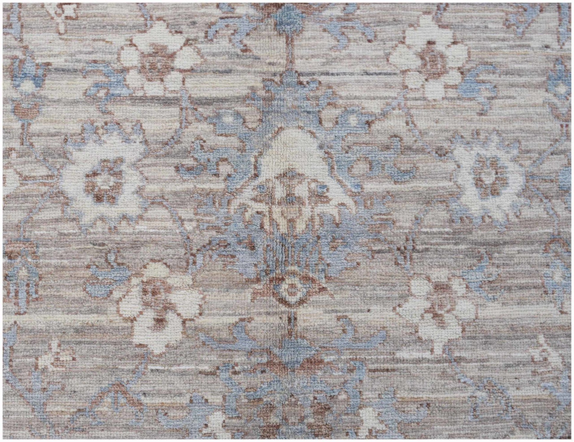 A transitional Oushak rug featuring a floral pattern in soft blue, beige, and brown tones.