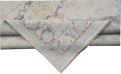 A handwoven transitional Oushak rug featuring a floral pattern in soft pastel and grey tones.