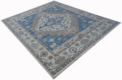 A rectangular transitional Oushak rug featuring a blue and beige geometric medallion pattern.