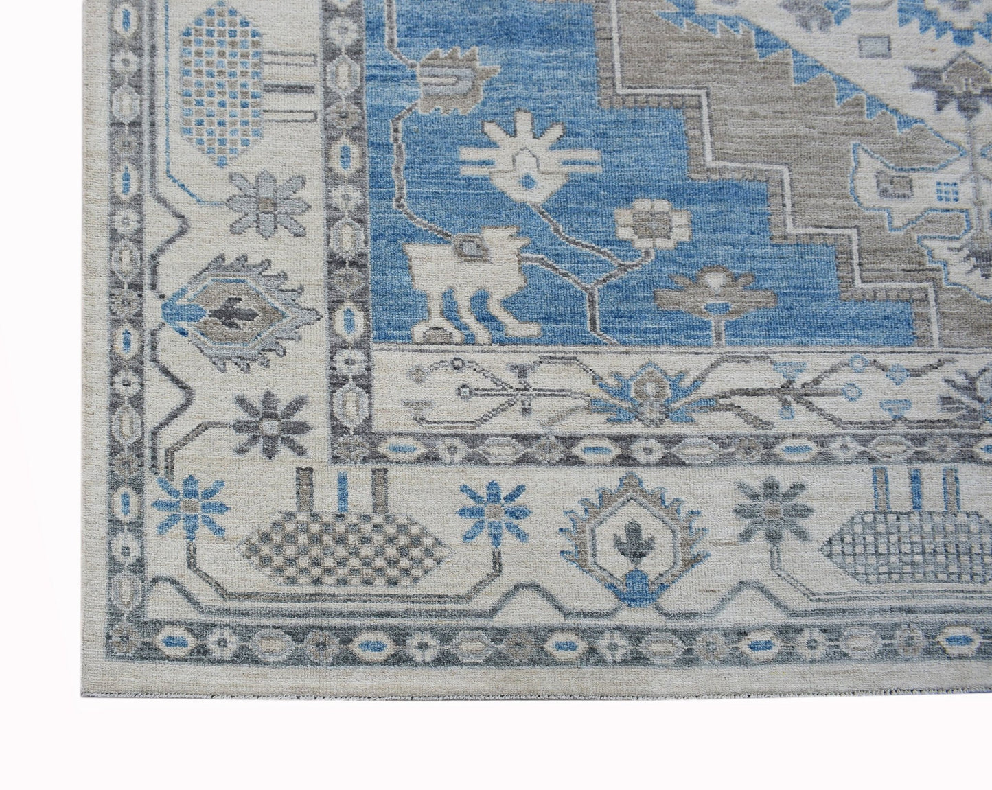 A transitional Oushak rug featuring a blue and beige geometric pattern with floral motifs.