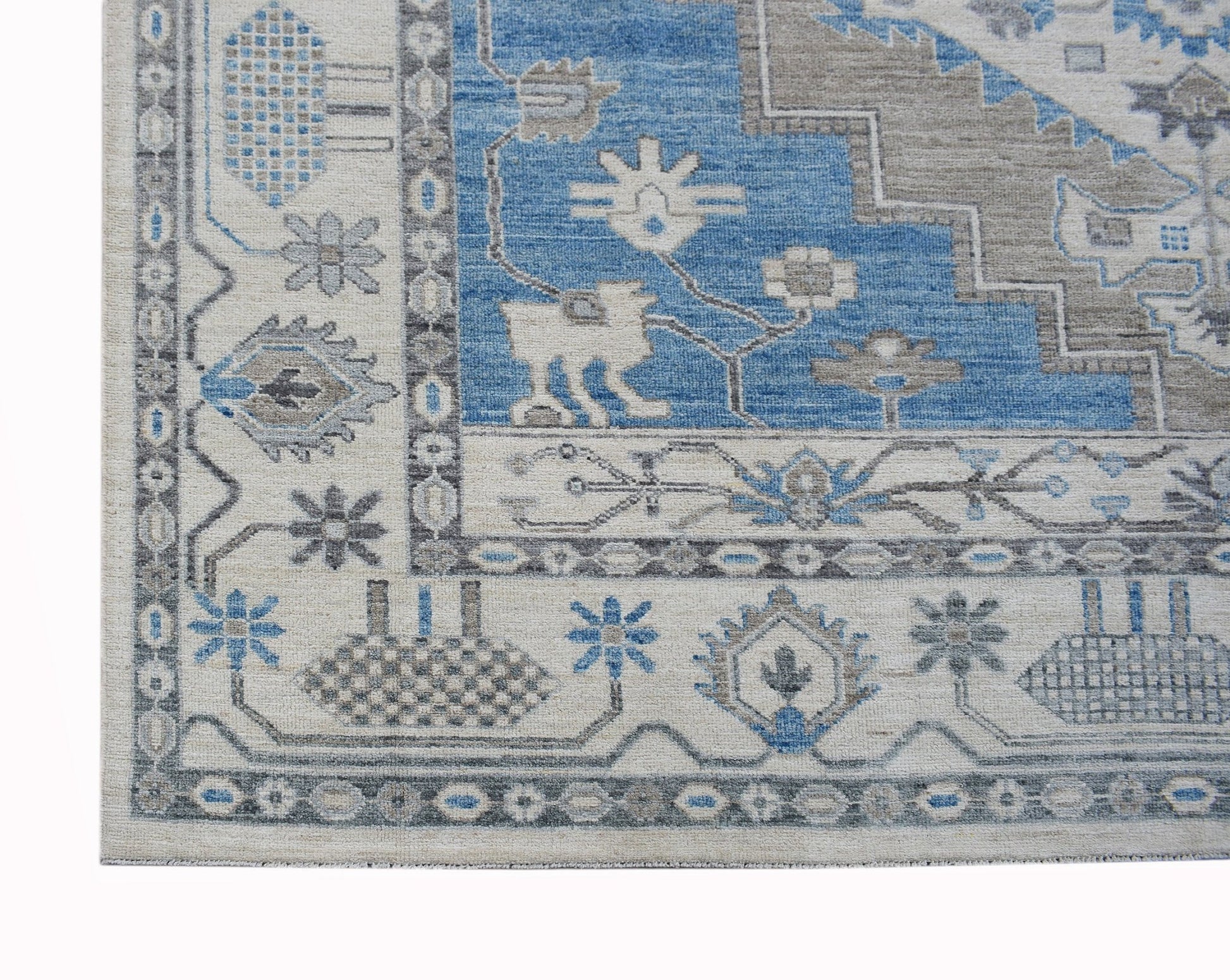 A transitional Oushak rug featuring a blue and beige geometric pattern with floral motifs.