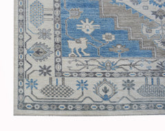 A transitional Oushak rug featuring a blue and beige geometric pattern with floral motifs.