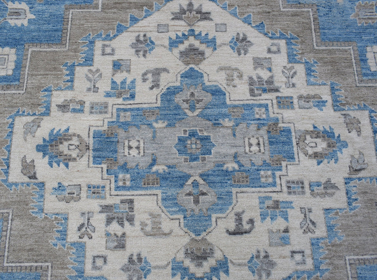 A handmade transitional Oushak rug featuring a blue, grey, and cream geometric medallion pattern.
