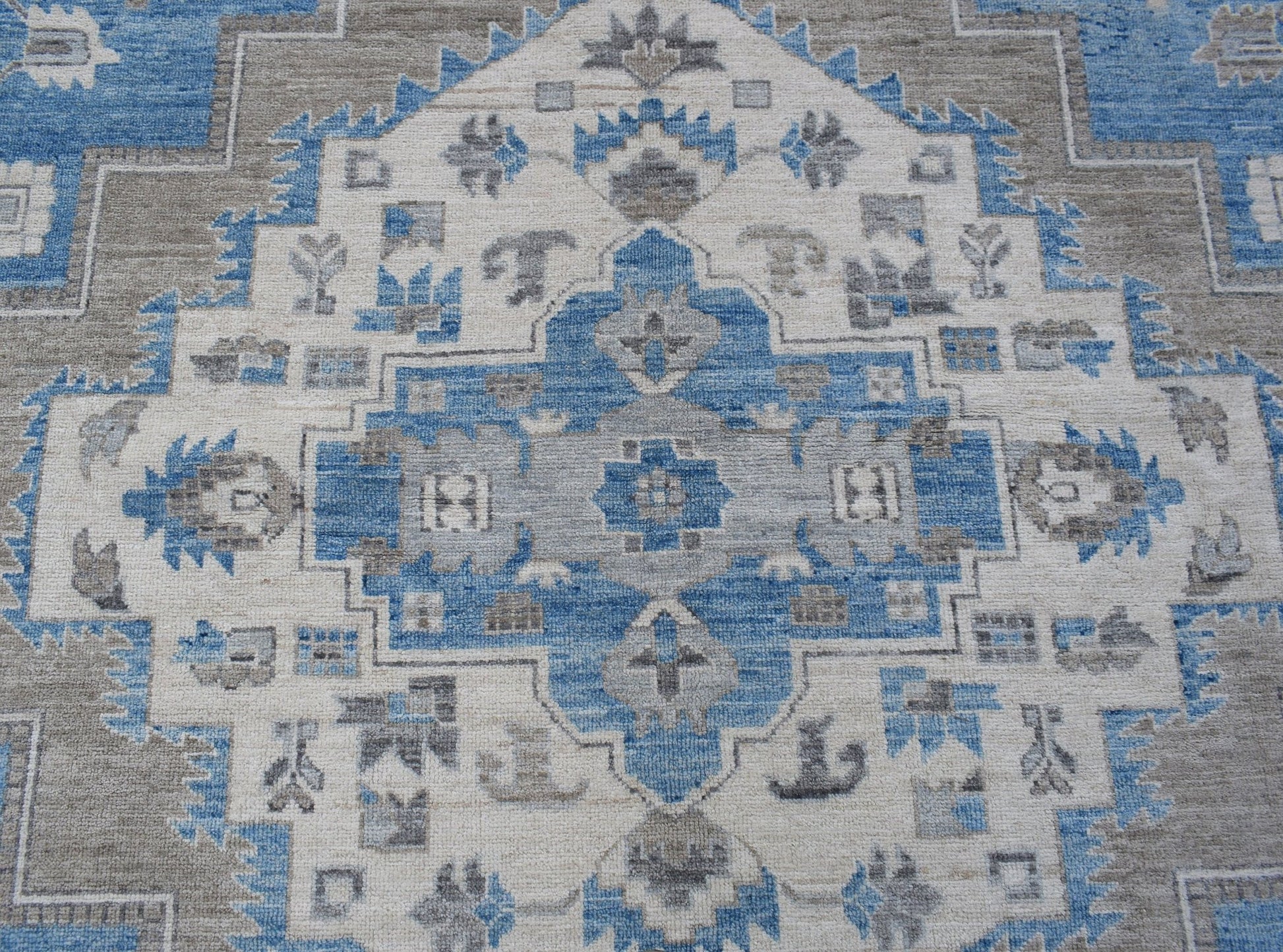 A handmade transitional Oushak rug featuring a blue, grey, and cream geometric medallion pattern.