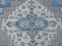 A handmade transitional Oushak rug featuring a blue, grey, and cream geometric medallion pattern.