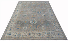 A handwoven transitional Oushak rug featuring a floral pattern in blue and tan on a grey field.