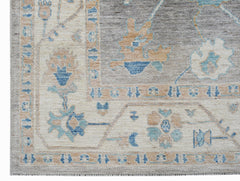 A transitional Oushak rug featuring a floral pattern in blue, beige, and grey tones.
