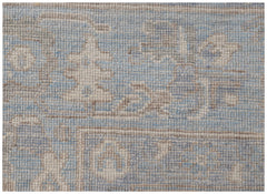 A handmade wool rug featuring a traditional Oushak pattern in soft blue and beige tones.