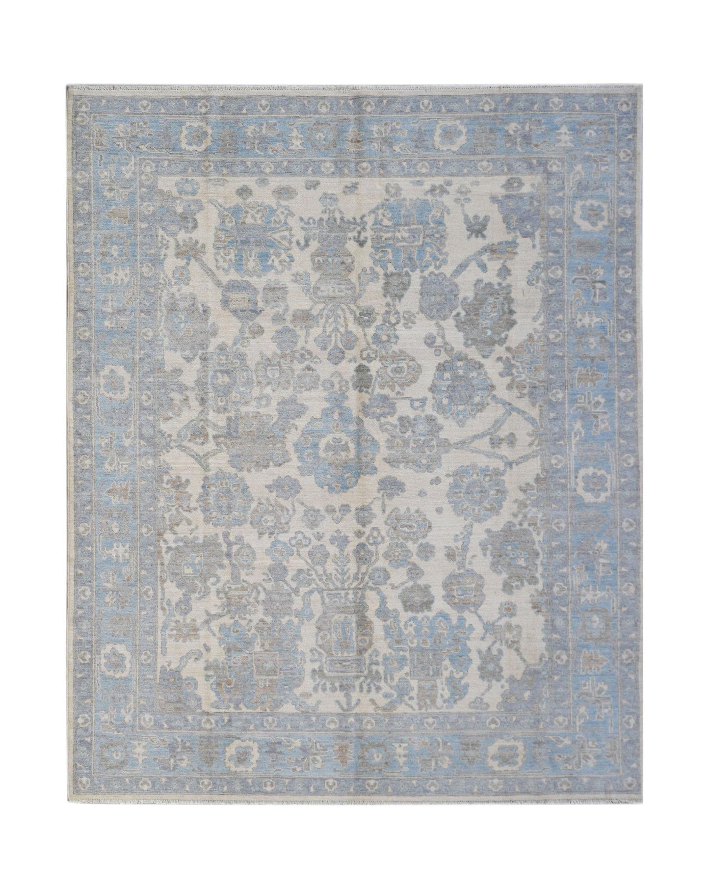 A handmade transitional Oushak rug featuring a soft blue and grey floral pattern on a cream base.