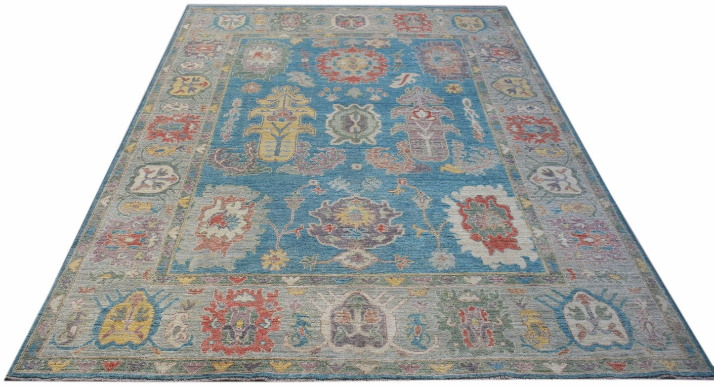 A handwoven transitional Oushak rug featuring a floral pattern in blue and multi-colored tones.