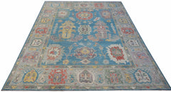 A handwoven transitional Oushak rug featuring a floral pattern in blue and multi-colored tones.