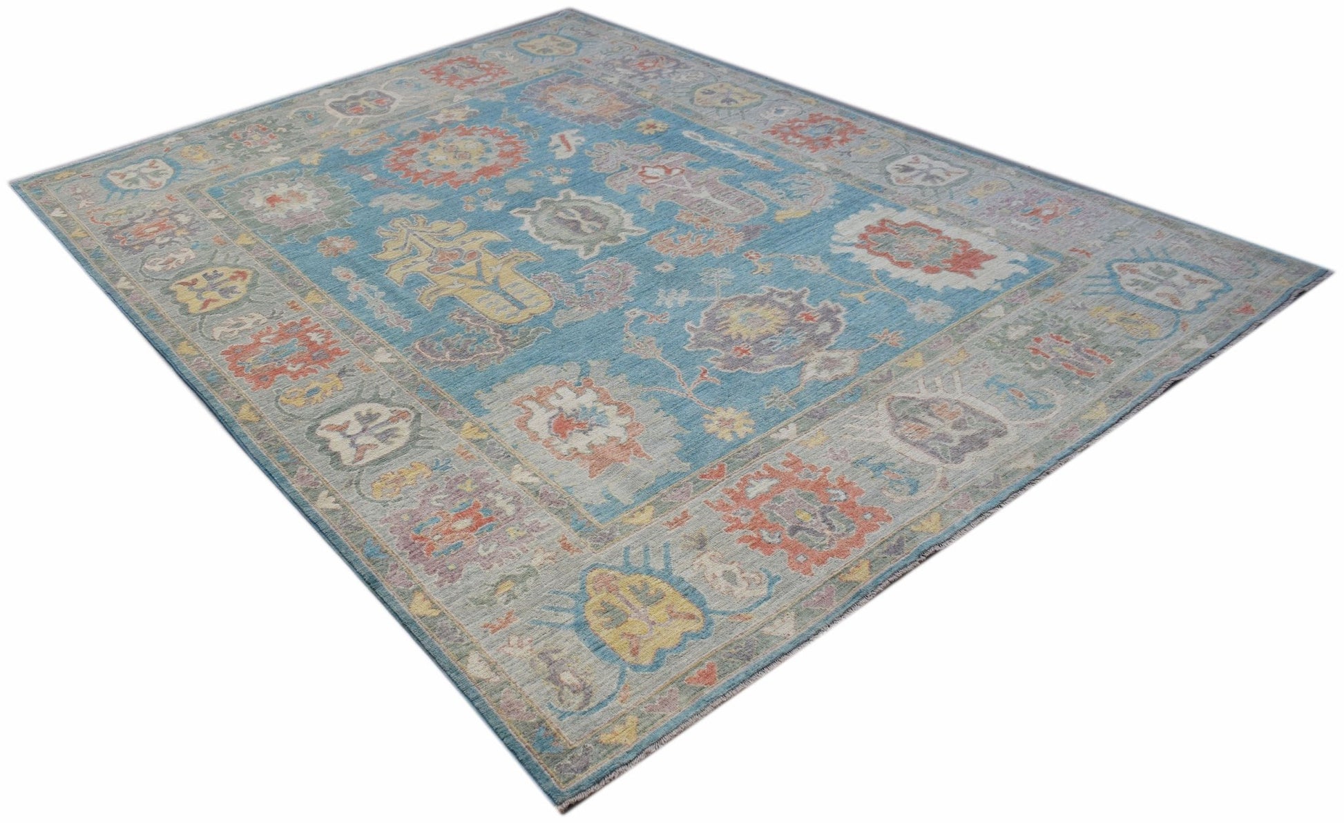 A handwoven transitional Oushak rug featuring a floral pattern in blue and multi-colored tones.
