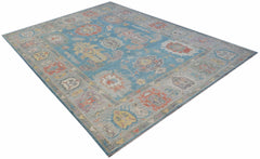 A handwoven transitional Oushak rug featuring a floral pattern in blue and multi-colored tones.