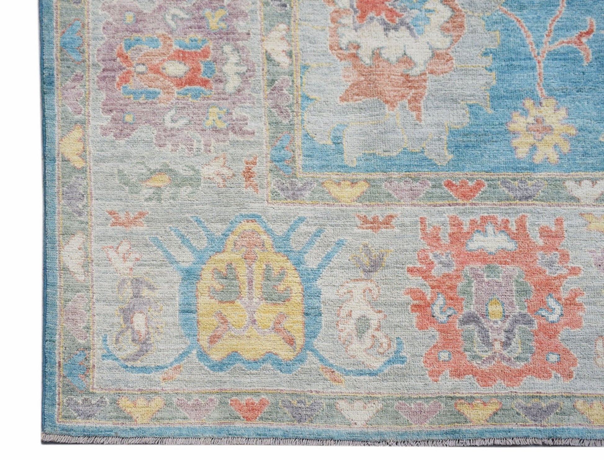 A handwoven transitional Oushak rug featuring a floral pattern in soft blue, coral, and yellow.