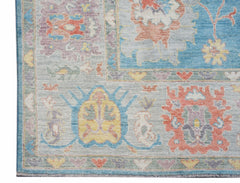 A handwoven transitional Oushak rug featuring a floral pattern in soft blue, coral, and yellow.