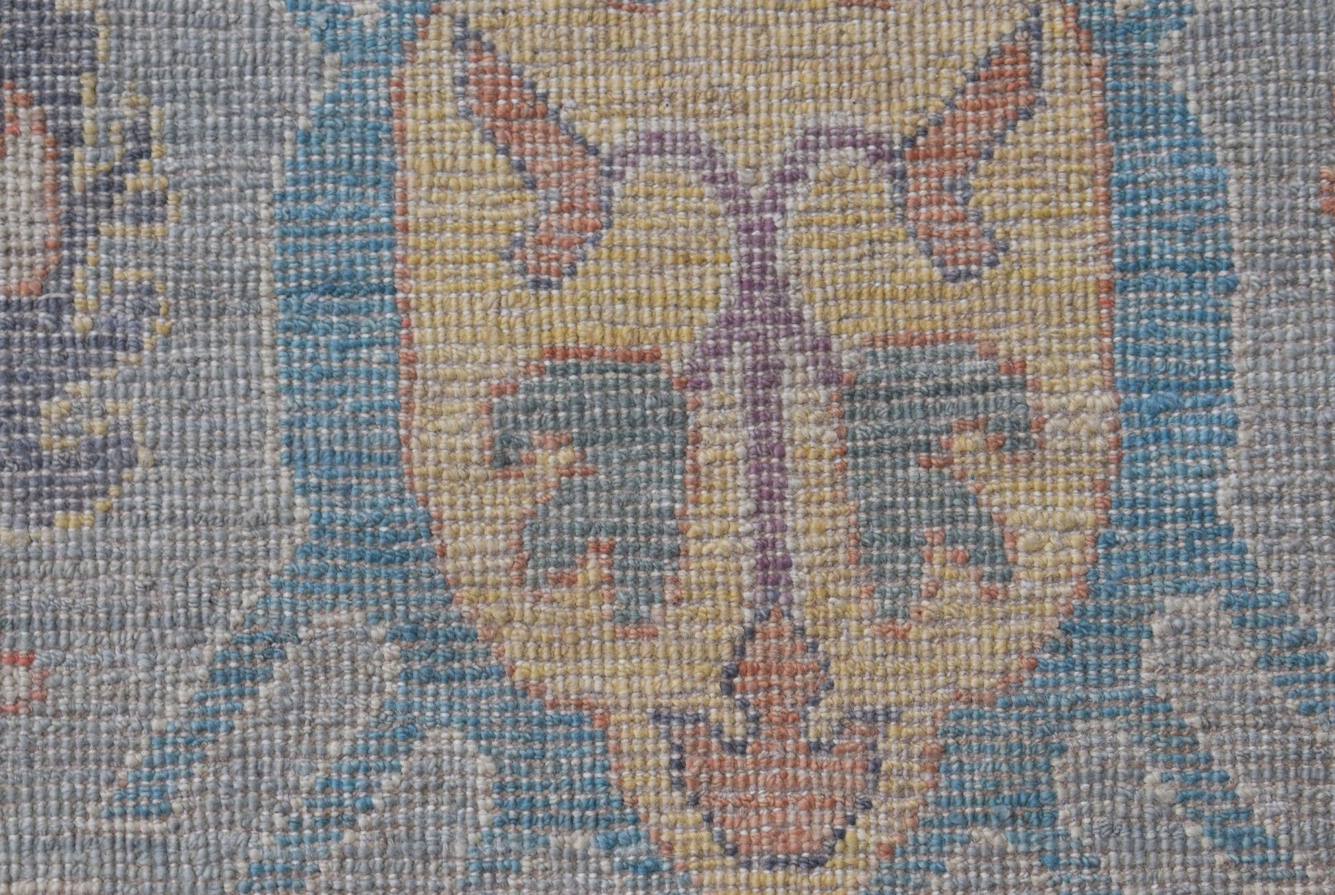 A close-up of a handwoven transitional Oushak rug featuring a floral pattern in muted tones.