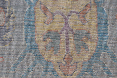 A close-up of a handwoven transitional Oushak rug featuring a floral pattern in muted tones.
