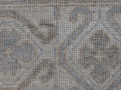 A close-up view of a handwoven transitional Oushak rug featuring a soft, neutral floral pattern.