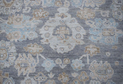 A handwoven transitional Oushak rug featuring a floral pattern in shades of grey, blue, and beige.