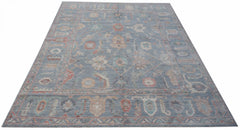 A handwoven transitional Oushak rug featuring a floral pattern in muted blue and earthy tones.