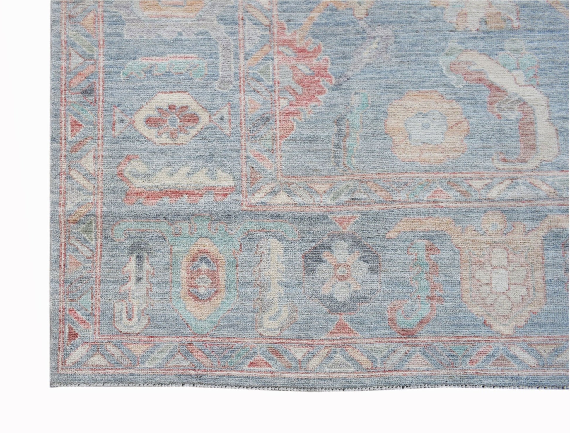 A handwoven transitional Oushak rug featuring a blue field with floral patterns and geometric borders.