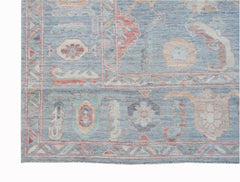 A handwoven transitional Oushak rug featuring a blue field with floral patterns and geometric borders.