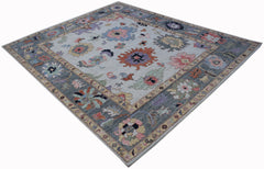 A handwoven transitional Oushak rug featuring a floral pattern in muted tones on a light background.