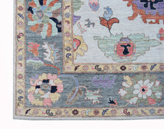 A transitional Oushak rug featuring a floral pattern in soft colors on a grey and cream background.