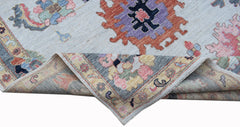 A handwoven transitional Oushak rug with a floral pattern in soft pastel and bold accent colors.