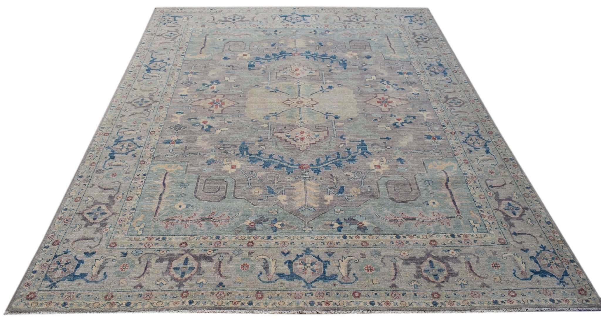 A handwoven transitional Oushak rug featuring a floral pattern in muted blue and grey tones.