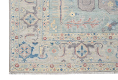 A handwoven transitional Oushak rug featuring a floral pattern in blue, grey, and cream tones.