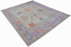 A handwoven transitional Oushak rug featuring a floral pattern in muted tones on a grey field.