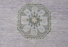 A handwoven transitional Oushak rug featuring a central floral medallion in soft lavender and grey.