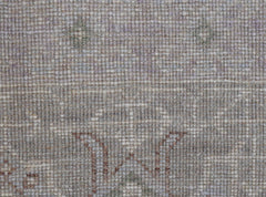 A close-up of a handwoven transitional Oushak rug featuring a subtle floral pattern in neutral tones.