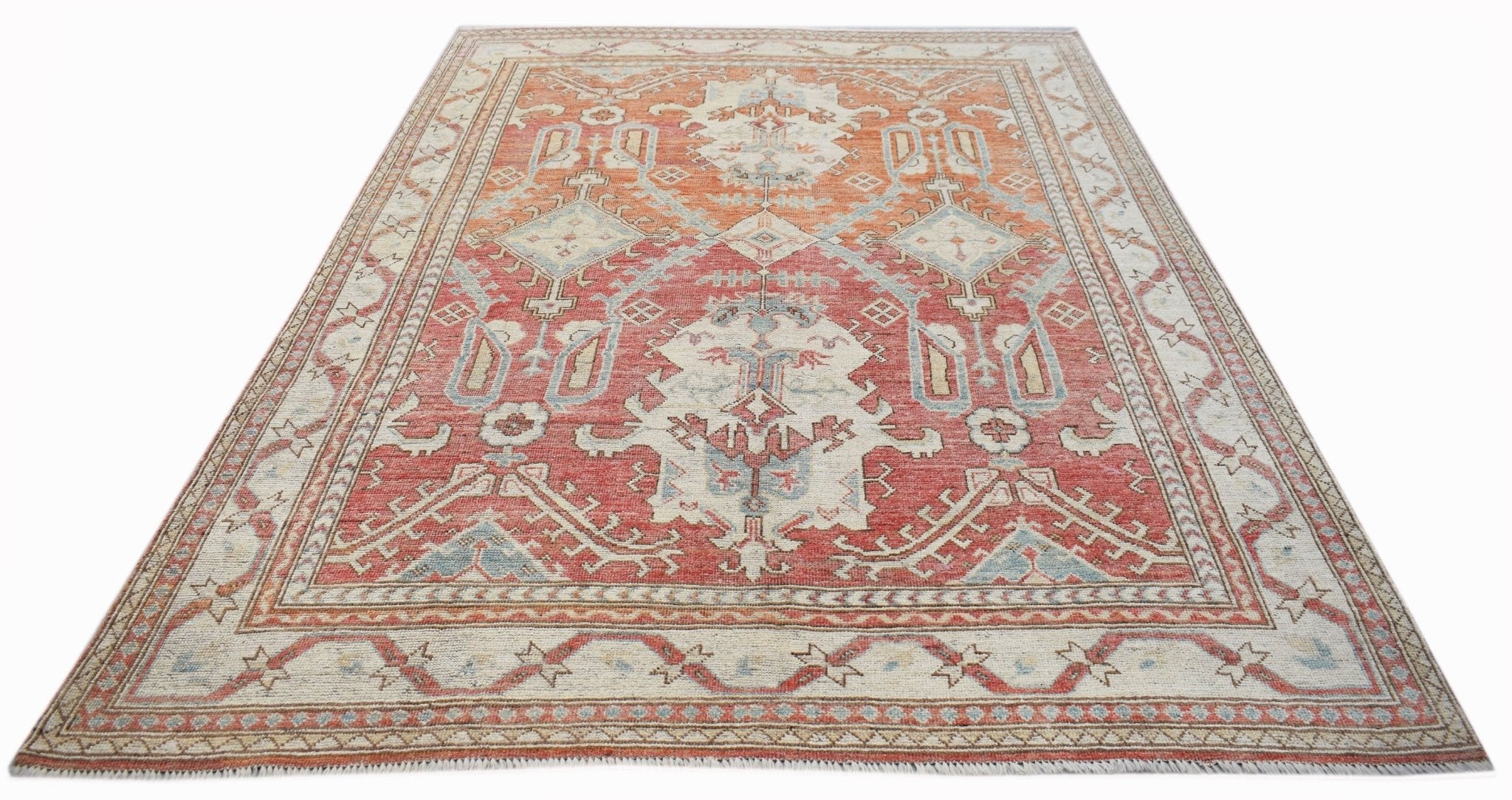 A handwoven transitional Oushak rug featuring a traditional floral pattern in red and blue tones.