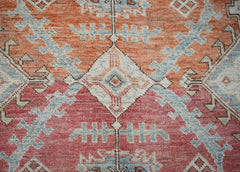 A handwoven transitional Oushak rug featuring a geometric pattern in orange, red, and blue tones.