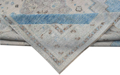 A handwoven transitional Oushak rug featuring a floral pattern in blue, grey, and beige tones.
