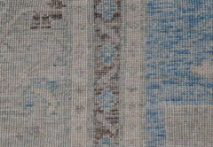 A close-up of a handwoven wool rug featuring a transitional pattern in blue, beige, and brown.