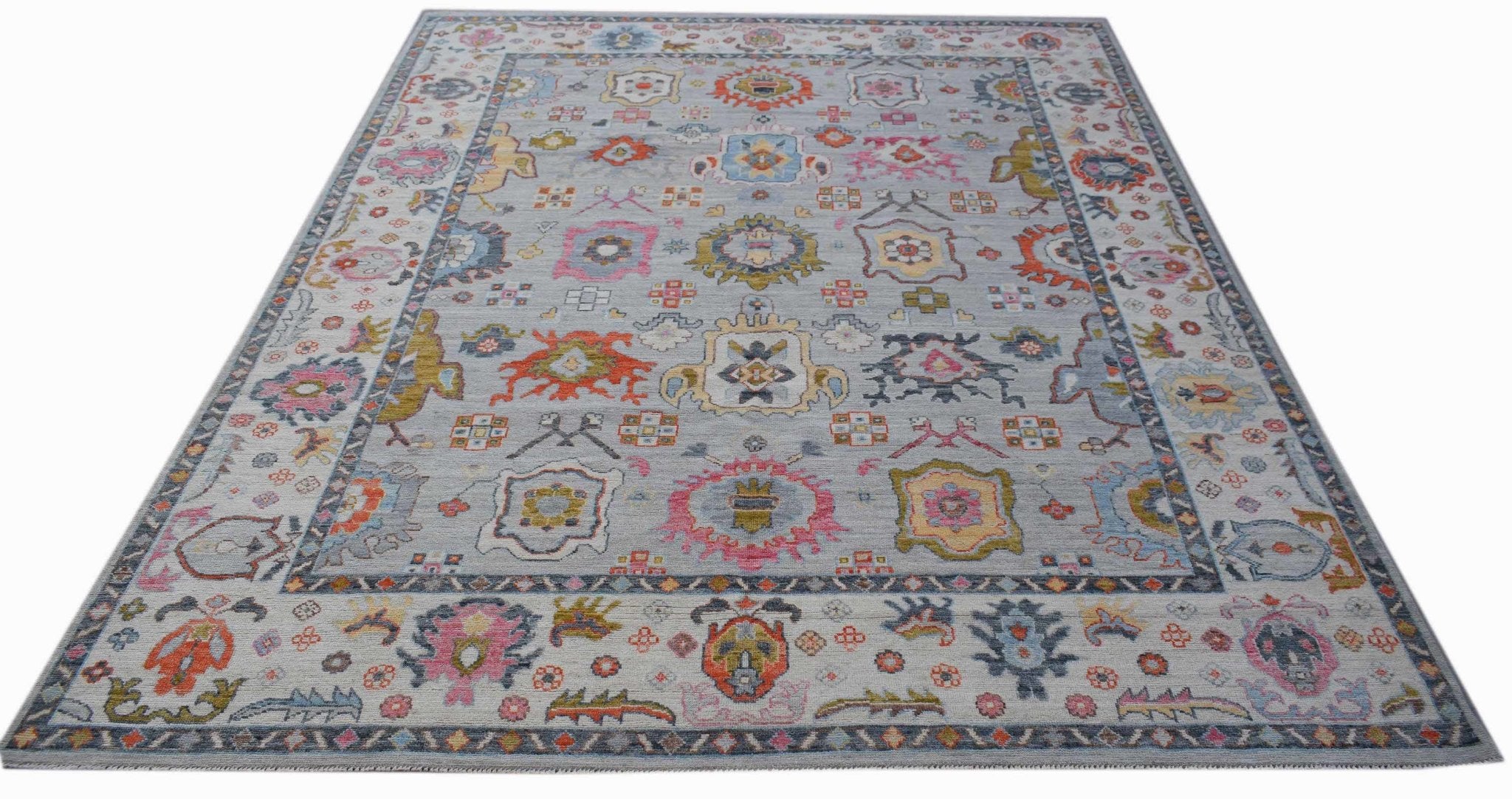 A handwoven transitional Oushak rug featuring a colorful floral pattern on a light grey background.