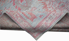 A handwoven transitional Oushak rug featuring a floral pattern in soft pink and blue tones.