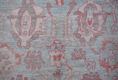 A handwoven wool Oushak rug featuring a transitional floral pattern in soft blue, pink, and grey.