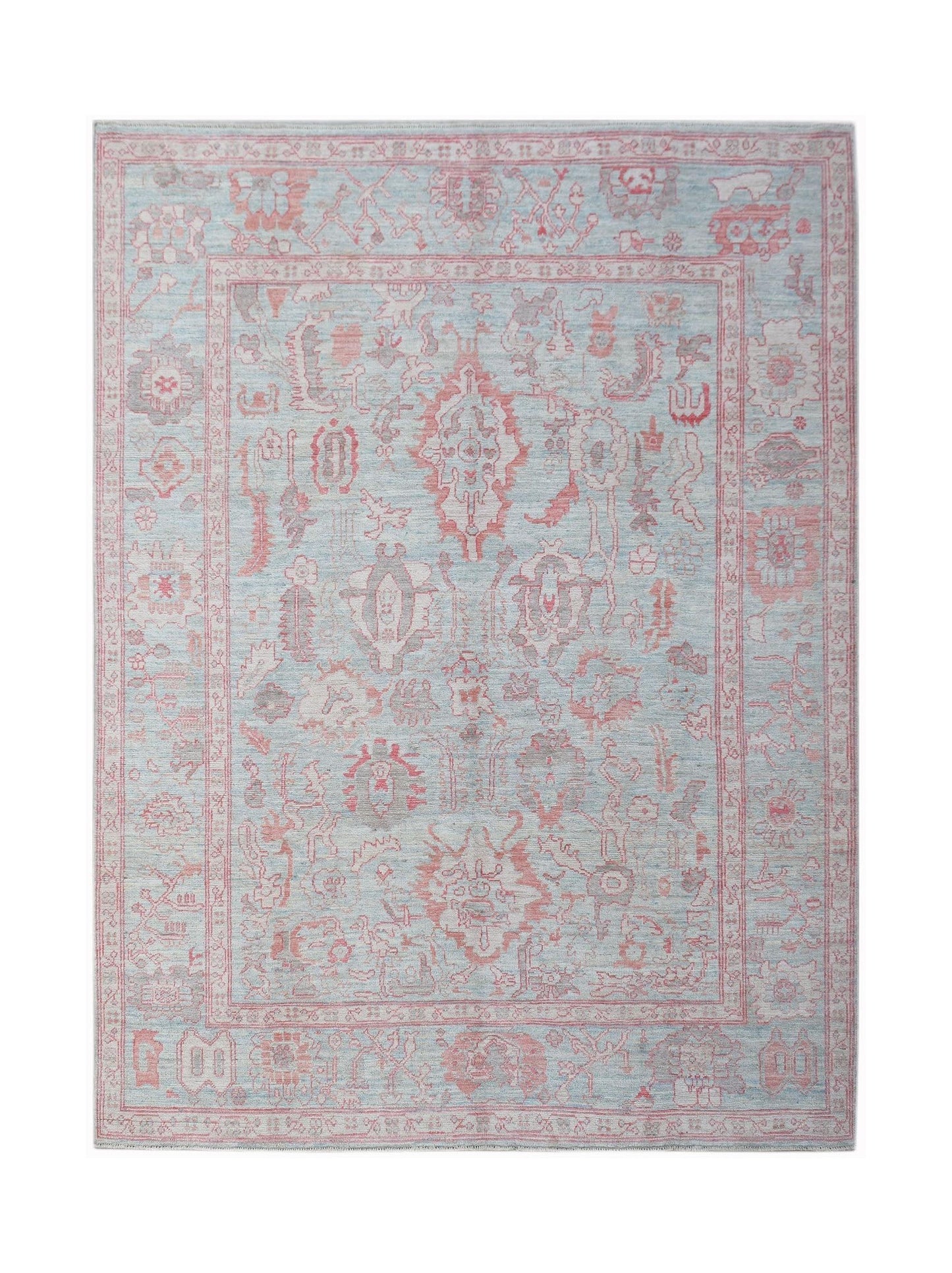 A handwoven transitional Oushak rug featuring a floral pattern in soft blue and pink tones.