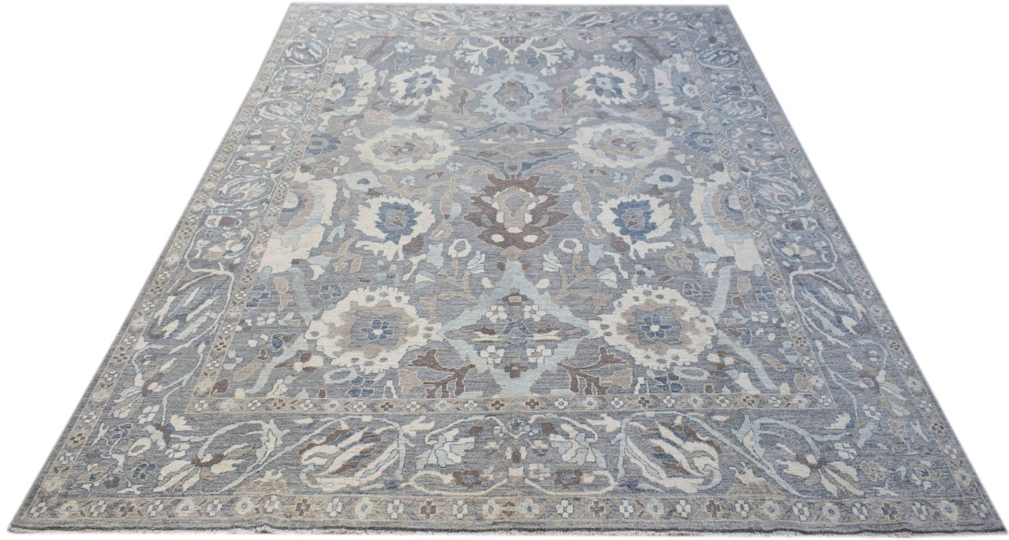 A handwoven transitional Oushak rug featuring a floral pattern in shades of blue, grey, and cream.