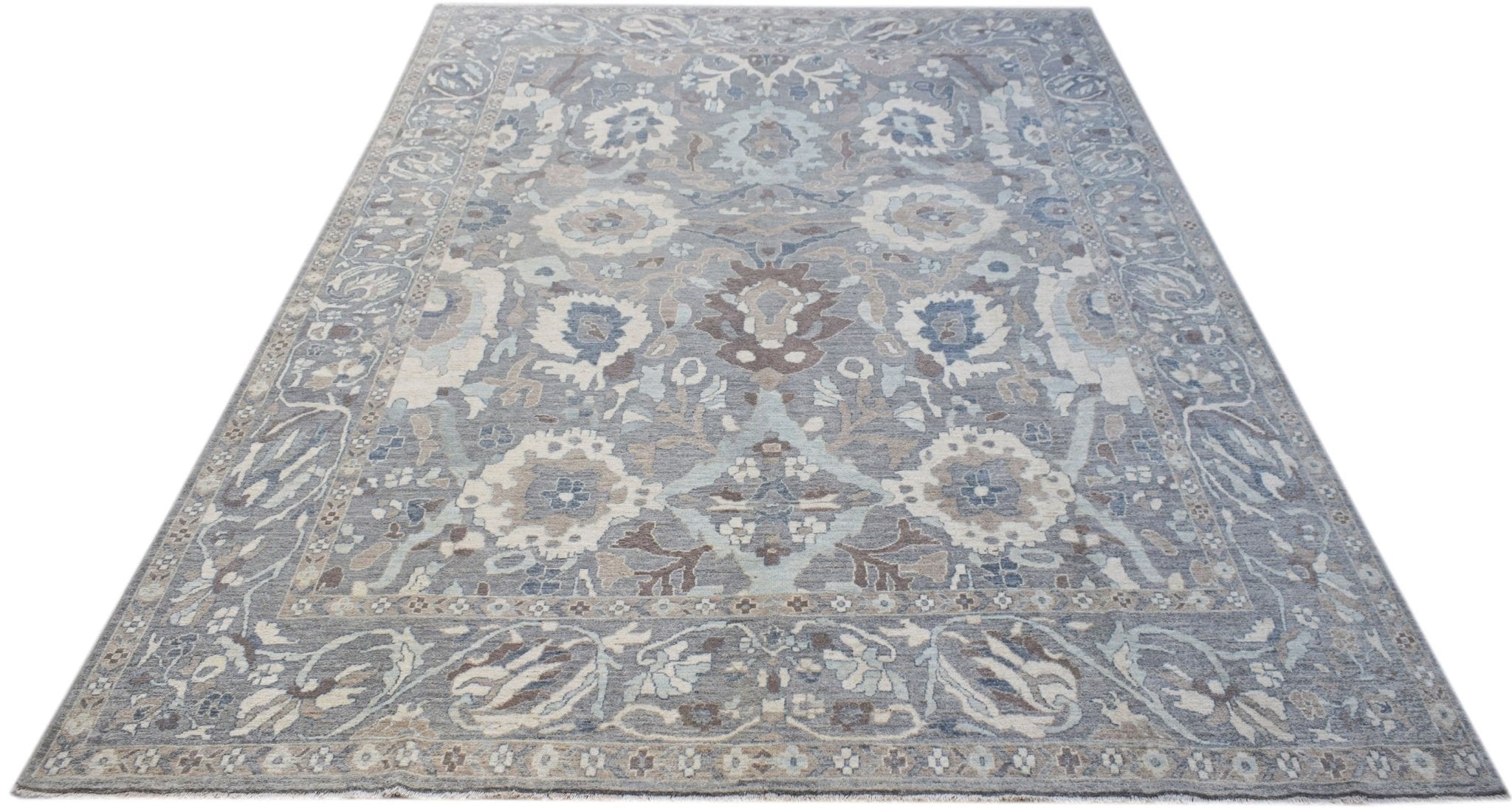 A handwoven transitional Oushak rug featuring a floral pattern in shades of blue, grey, and cream.