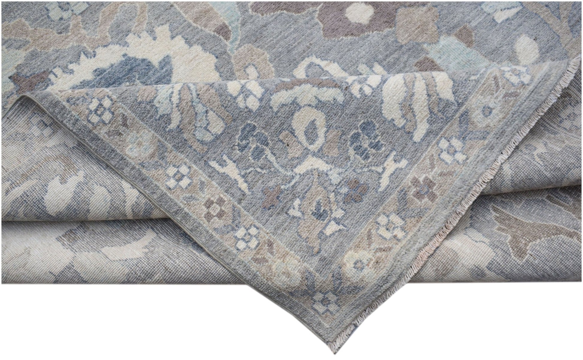 A handwoven transitional Oushak rug in shades of blue and grey with a floral pattern.