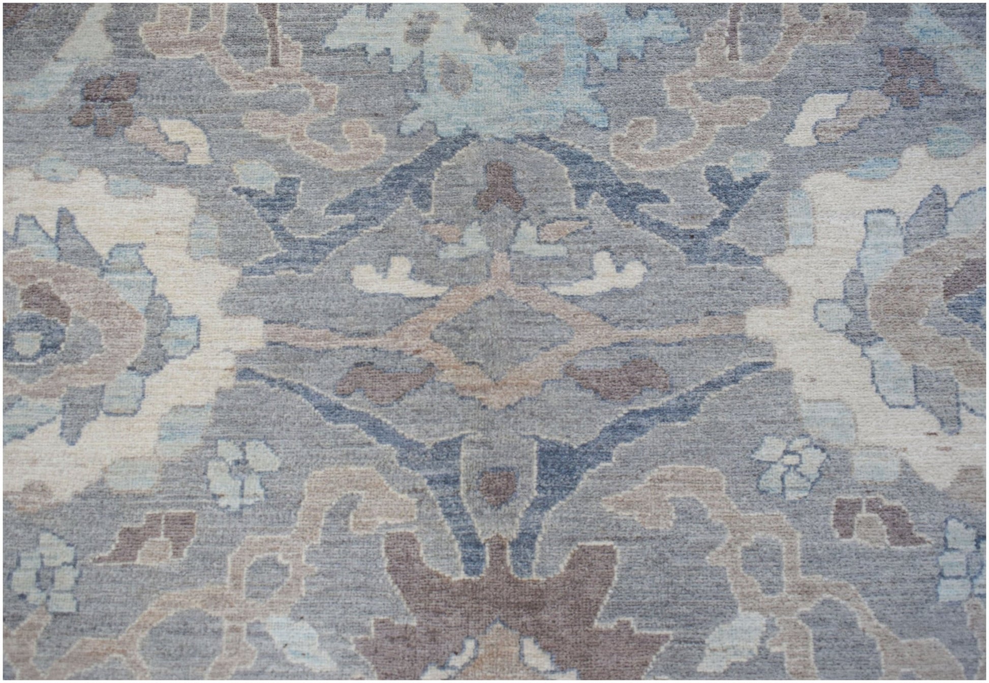 A transitional Oushak rug featuring a floral pattern in shades of grey, blue, and beige.