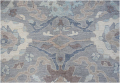A transitional Oushak rug featuring a floral pattern in shades of grey, blue, and beige.