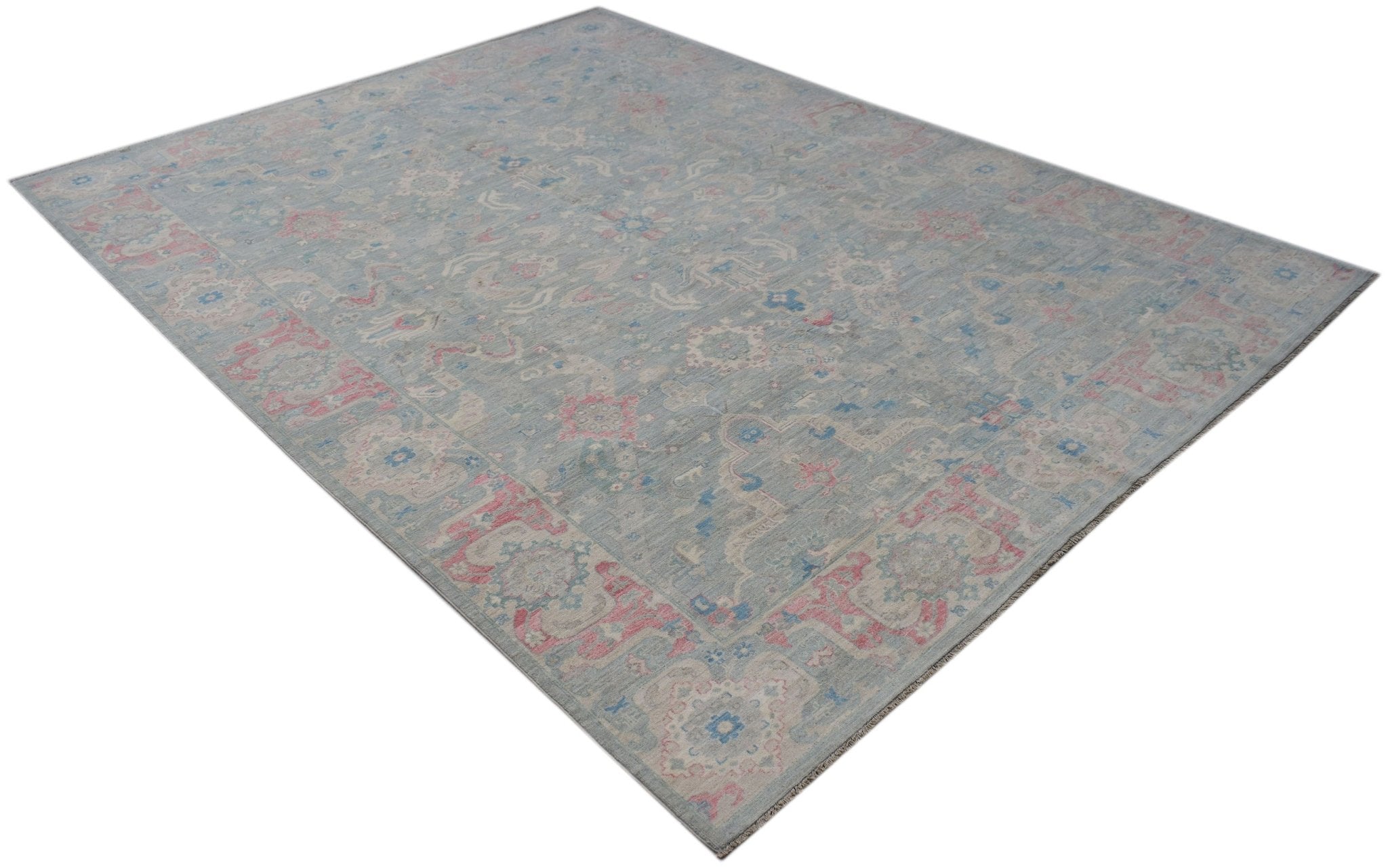 A handwoven transitional Oushak rug featuring a floral pattern in blue, pink, and cream tones.