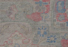 A close-up of a handwoven Oushak rug featuring a floral pattern in soft blue and pink tones.
